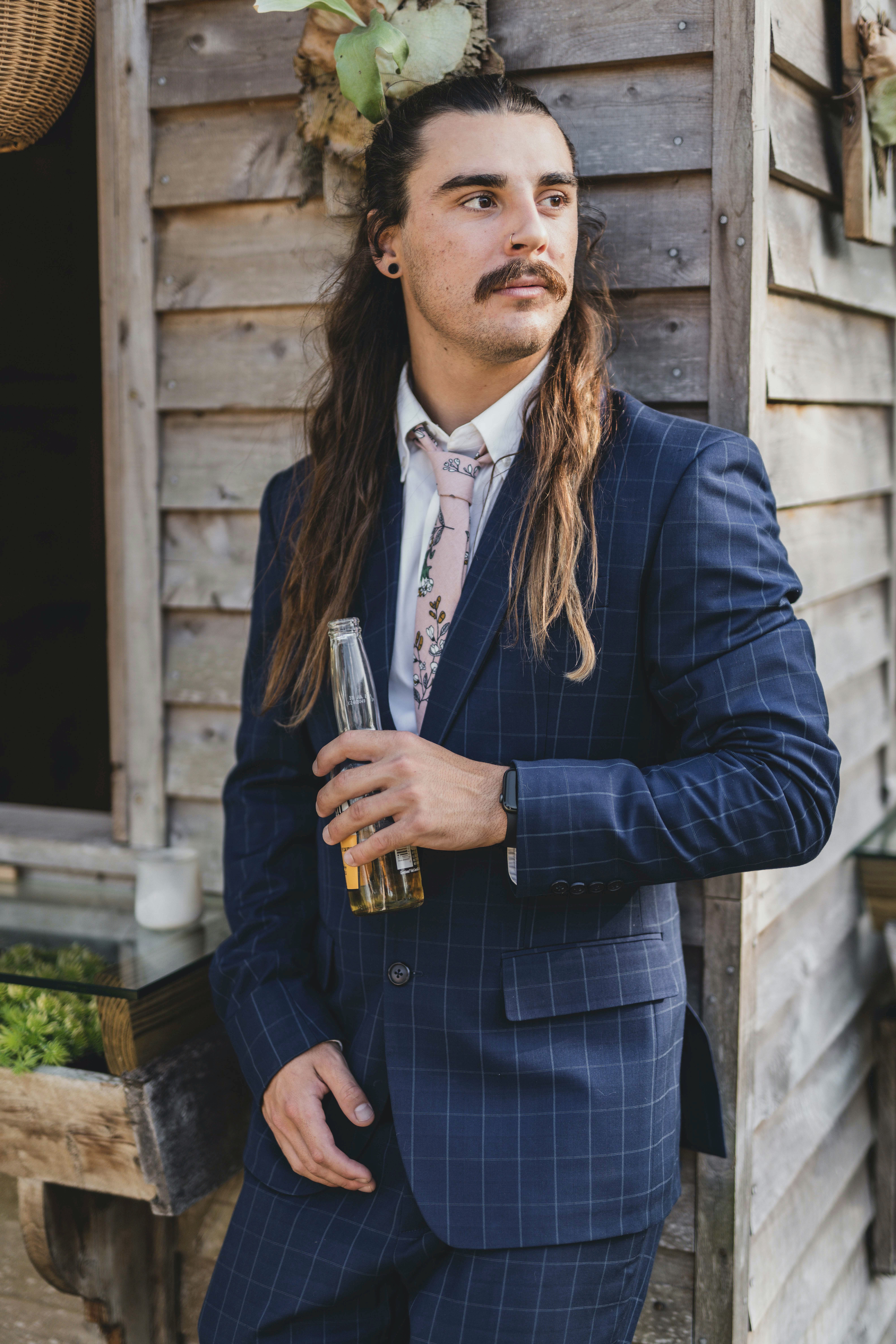 man in blue and white plaid suit holding glass bottle